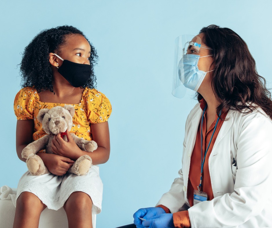Masked medical professional with young African American girl
